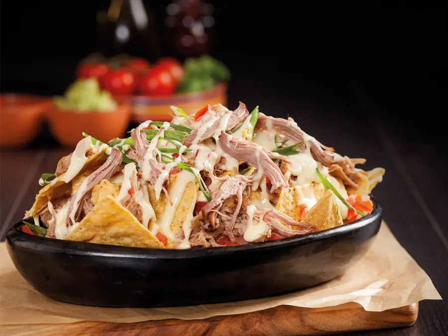 A cast iron bowl of loaded nachos