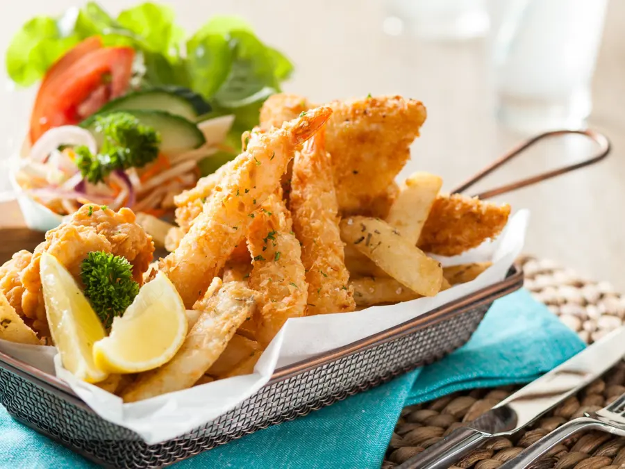 Crumbed fish and chips in a wire basket with salad