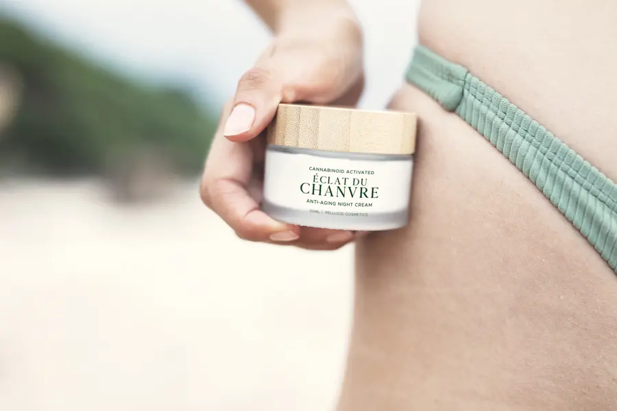 Close view of a hand holding a jar of body cream against a hip