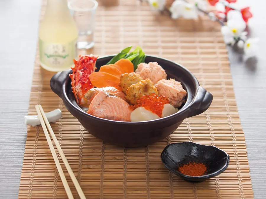 A Japanese hot pot with salmon and vegetables on a bamboo mat