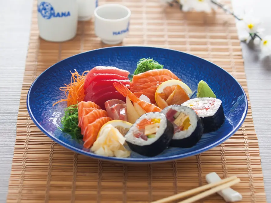 A blue plate of sashimi and sushi rolls