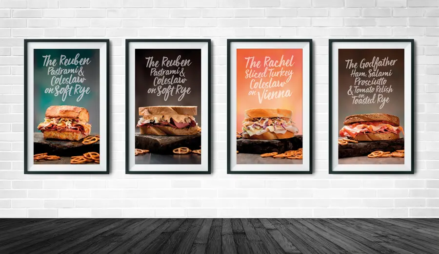 Four framed sandwich posters on a white brick wall