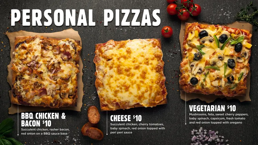 A Personal Pizzas menu board with three square pizzas on a dark background