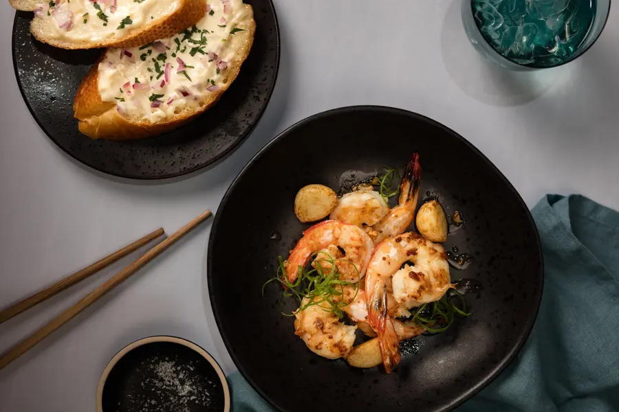 Garlic prawns in a black bowl with chopsticks