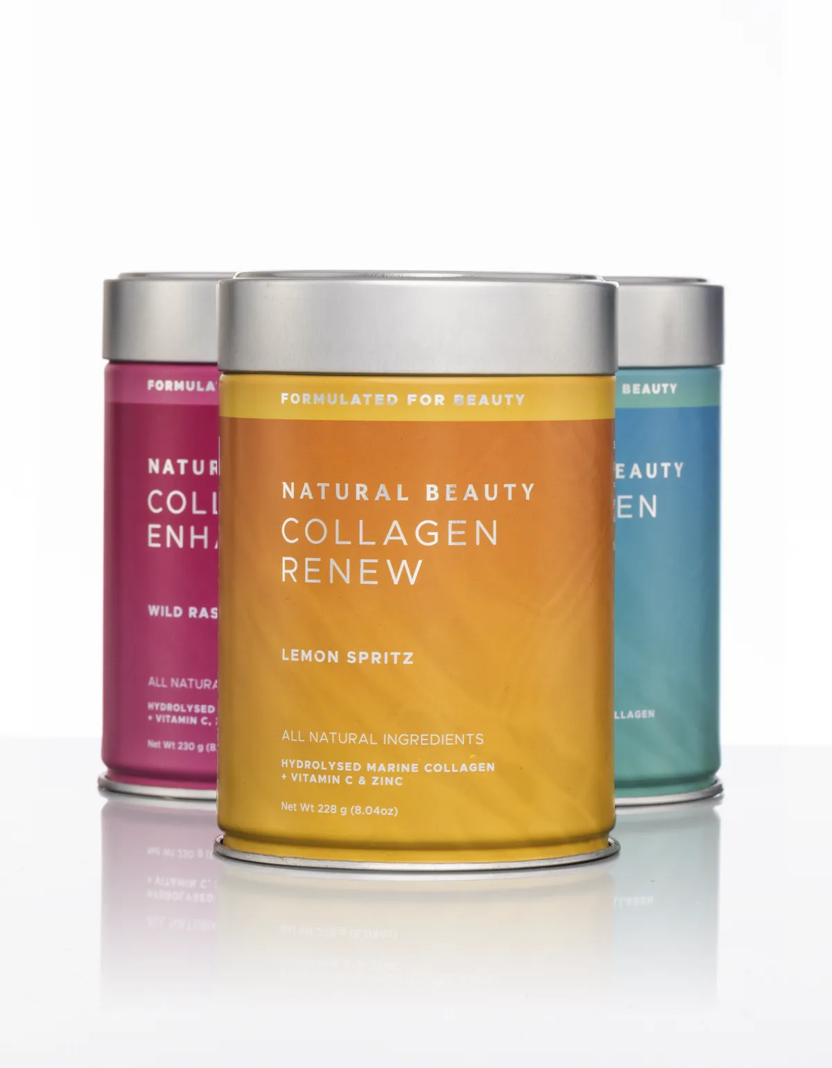 Three Natural Beauty collagen tins in a studio, with Collagen Renew in lemon spritz orange at the front