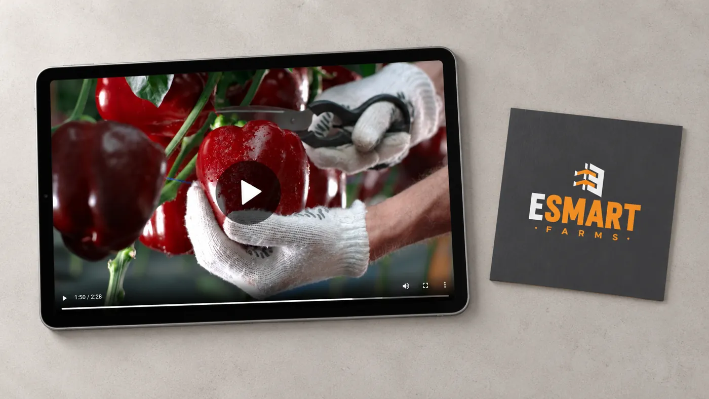 The ESmart Farms film playing on a tablet, beside a printed ESmart Farms logo card
