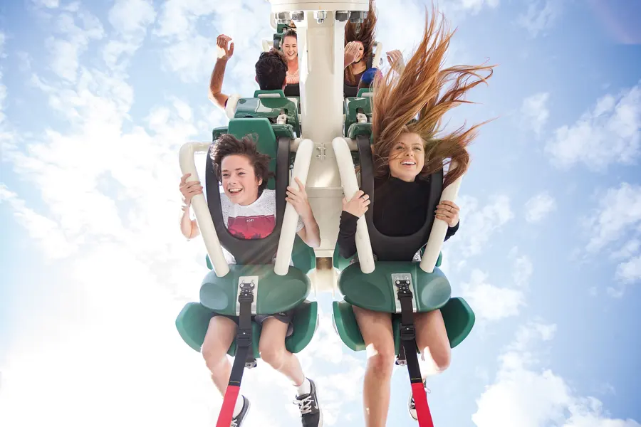 Two riders mid air on a thrill ride
