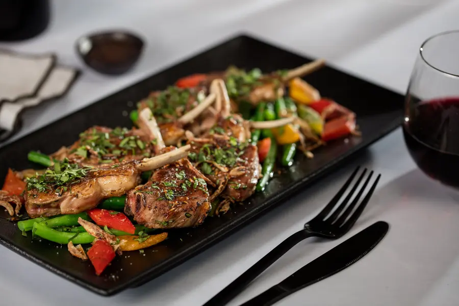 Lamb cutlets with greens on a black platter