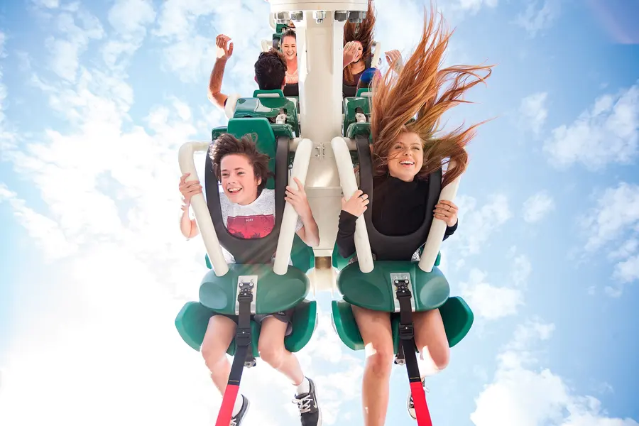 Riders laughing upside down against a blue sky
